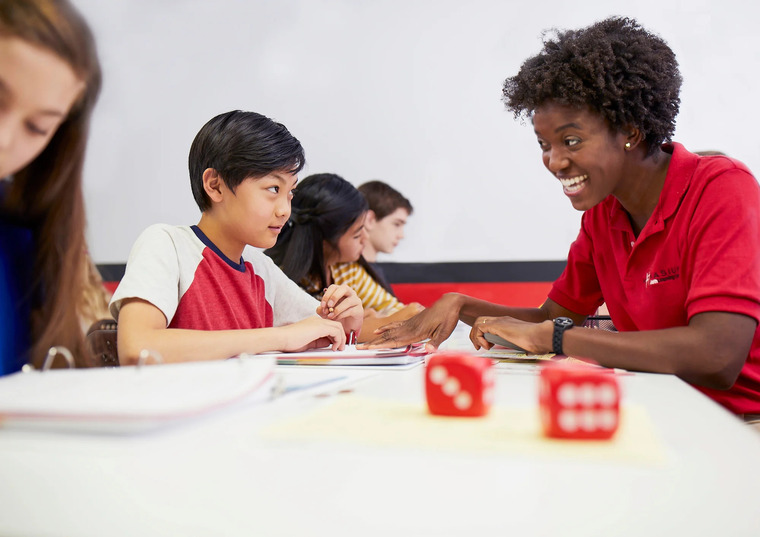 A teacher assists students with their homework, providing guidance and support in a classroom setting.