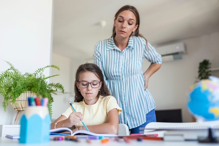 Parent watching daughter struggle with math homework, reflecting the disconnect between modern teaching methods and how parents learned math