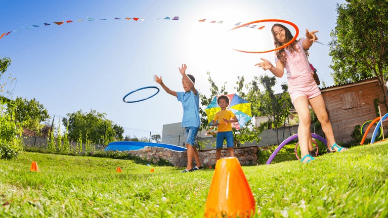 Two kids in backyard playing ring toss