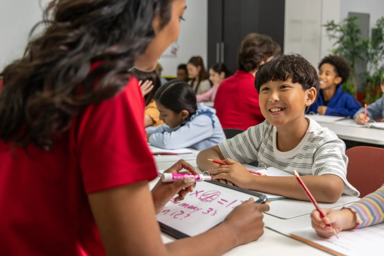 A classroom scene featuring a teacher guiding students as they learn together in a collaborative environment.