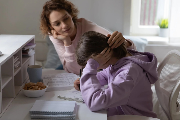 A woman is engaged in helping a child with homework, fostering a supportive and educational atmosphere.
