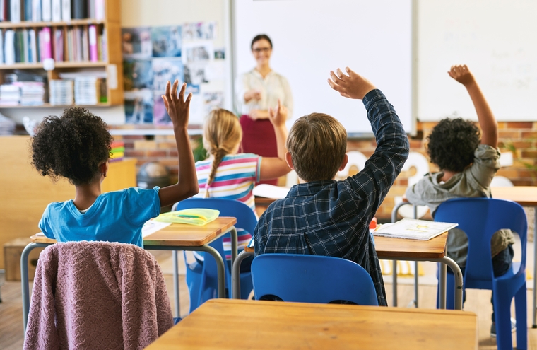 Students raising hands in class, actively engaged in learning