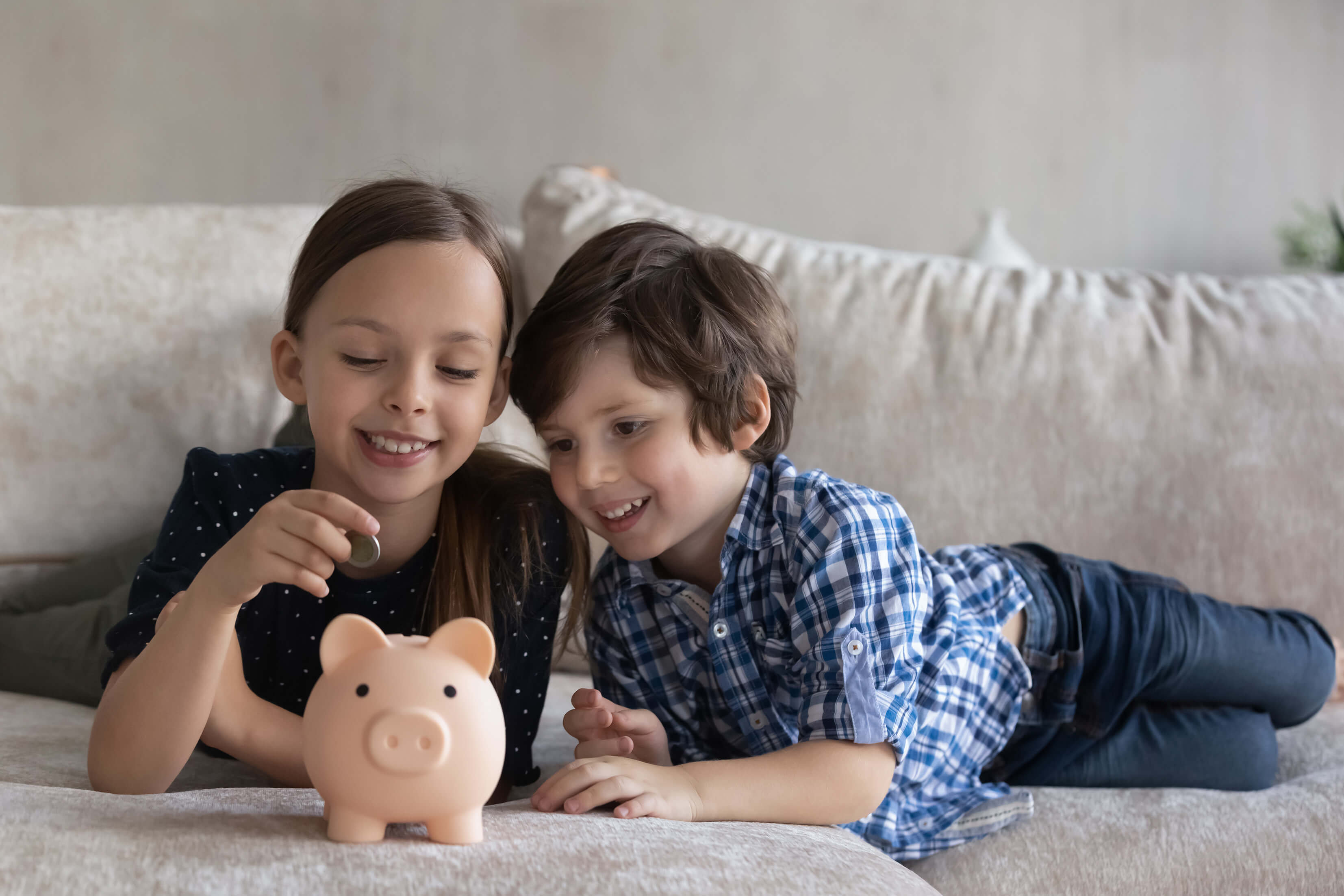 Children putting coins into a piggy bank.
