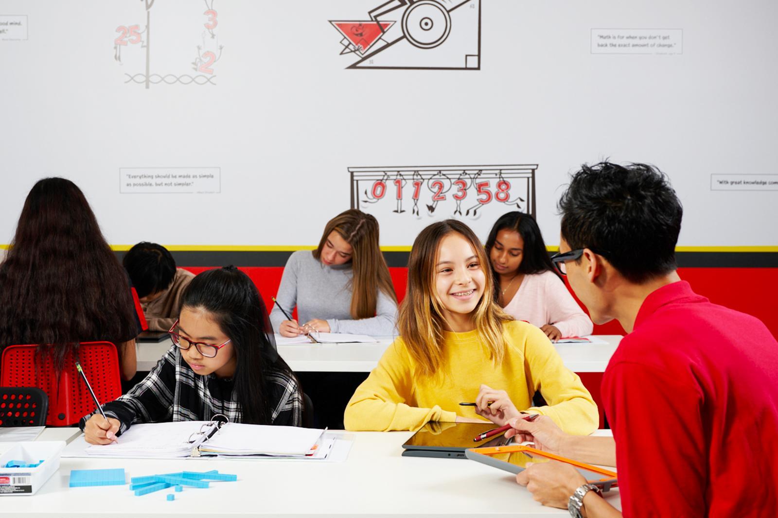 A classroom scene featuring a group of individuals sitting at a table, actively involved in a collaborative learning experience.