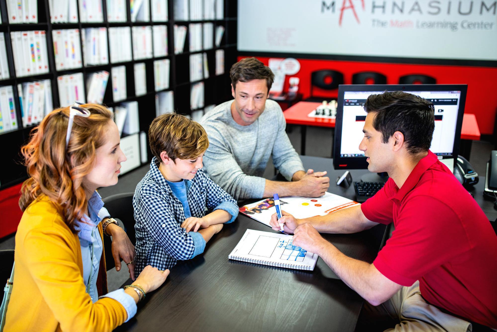 A family gathered around a table in a math classroom, engaged in a learning activity together.