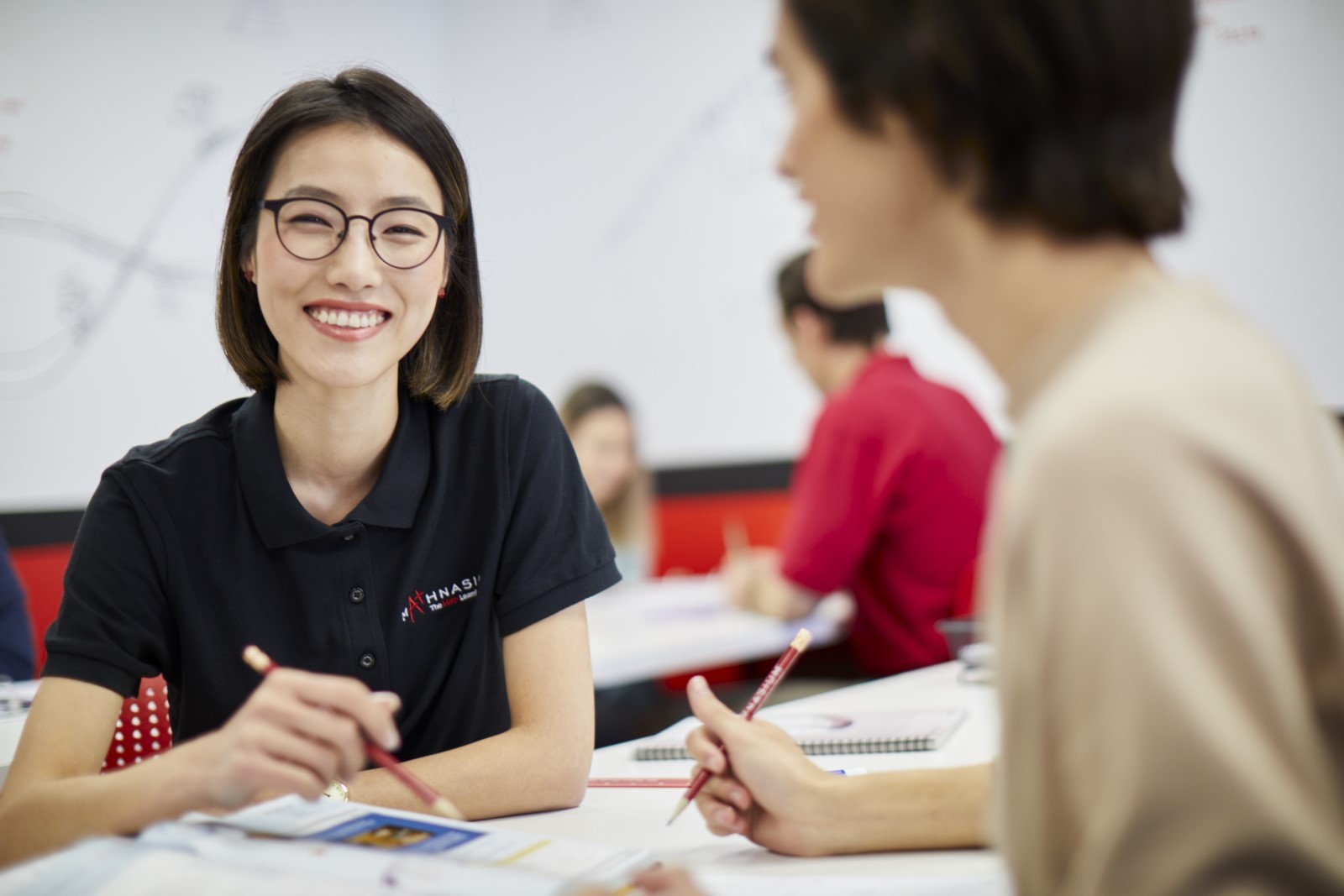 Photo of a Mathnasium geometry tutor smiling while working with a high school Mathnasium student