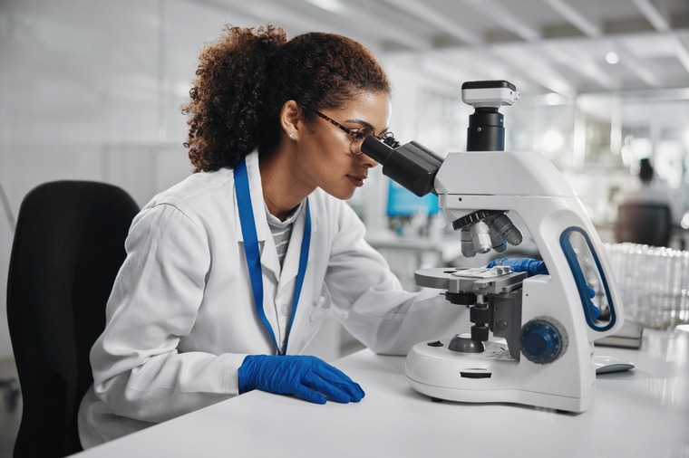 A scientist woman looking trough a microscope