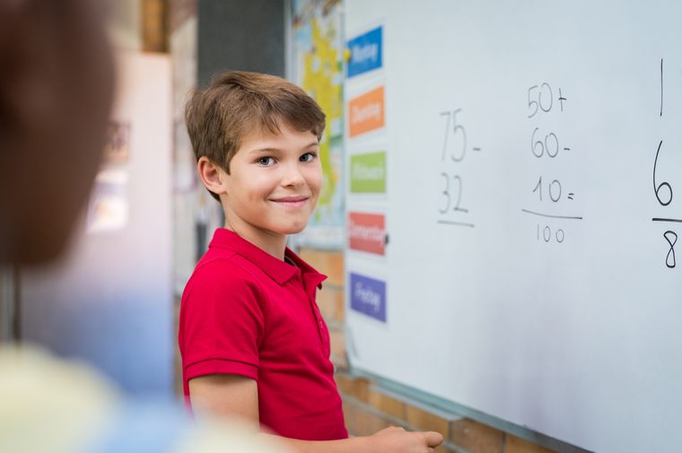 Kid doing math assignment on the board