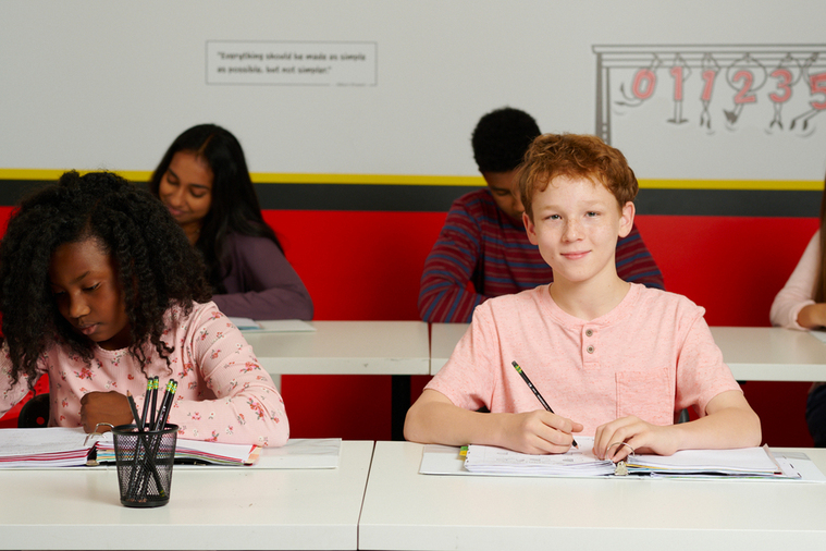 A ginger boy and a diverse girl studying math in the classroom