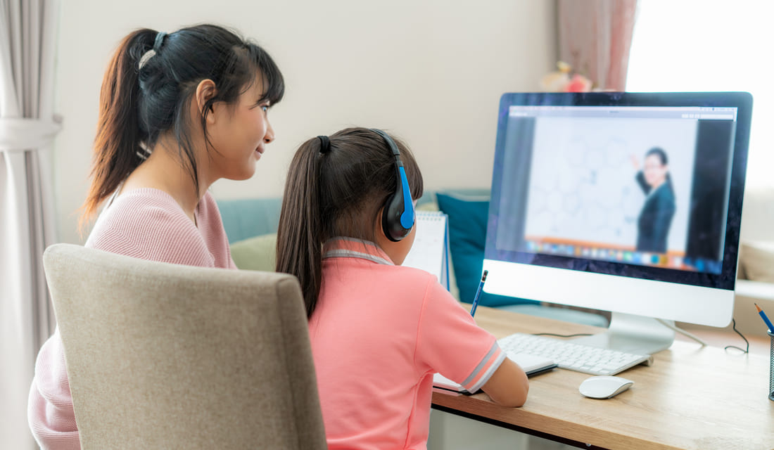 Math girl student with her mother having an online math class with her math tutor on computer at home.