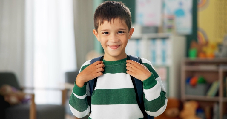 Smiling elementary school boy with backpack, showing confidence after after-school learning support