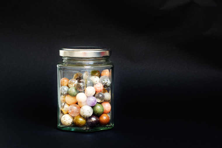 Glass jar filled with colorful marbles, used for a math estimation game to practice number sense