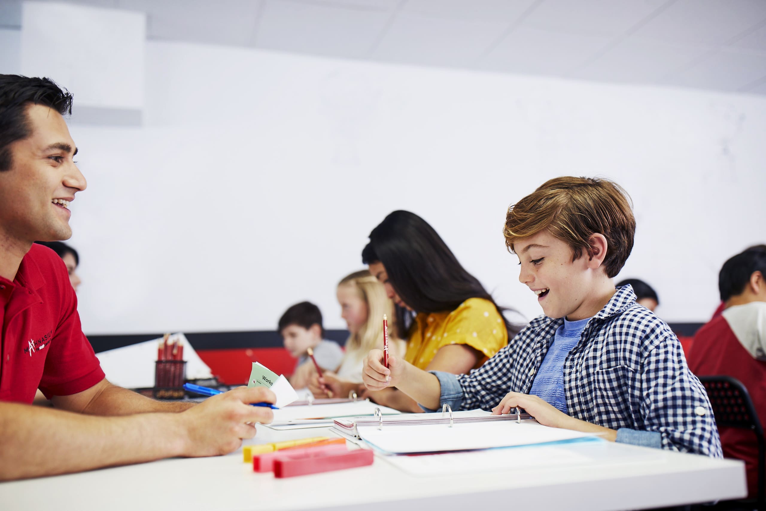 Boy smiles with excitement after solving a math problem with the help of a Mathnasium tutor.