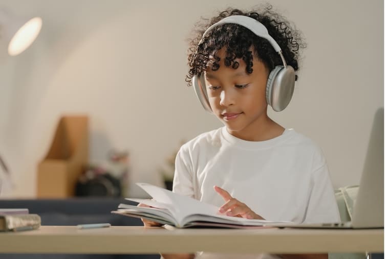 A young girl with headphones is engrossed in reading a book, showcasing her love for literature and music.