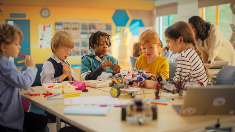 Children engaged in creative play with colorful LEGO bricks in a bright classroom setting.