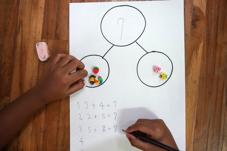 Child using small objects and number bond diagram to model combinations that add up to 7