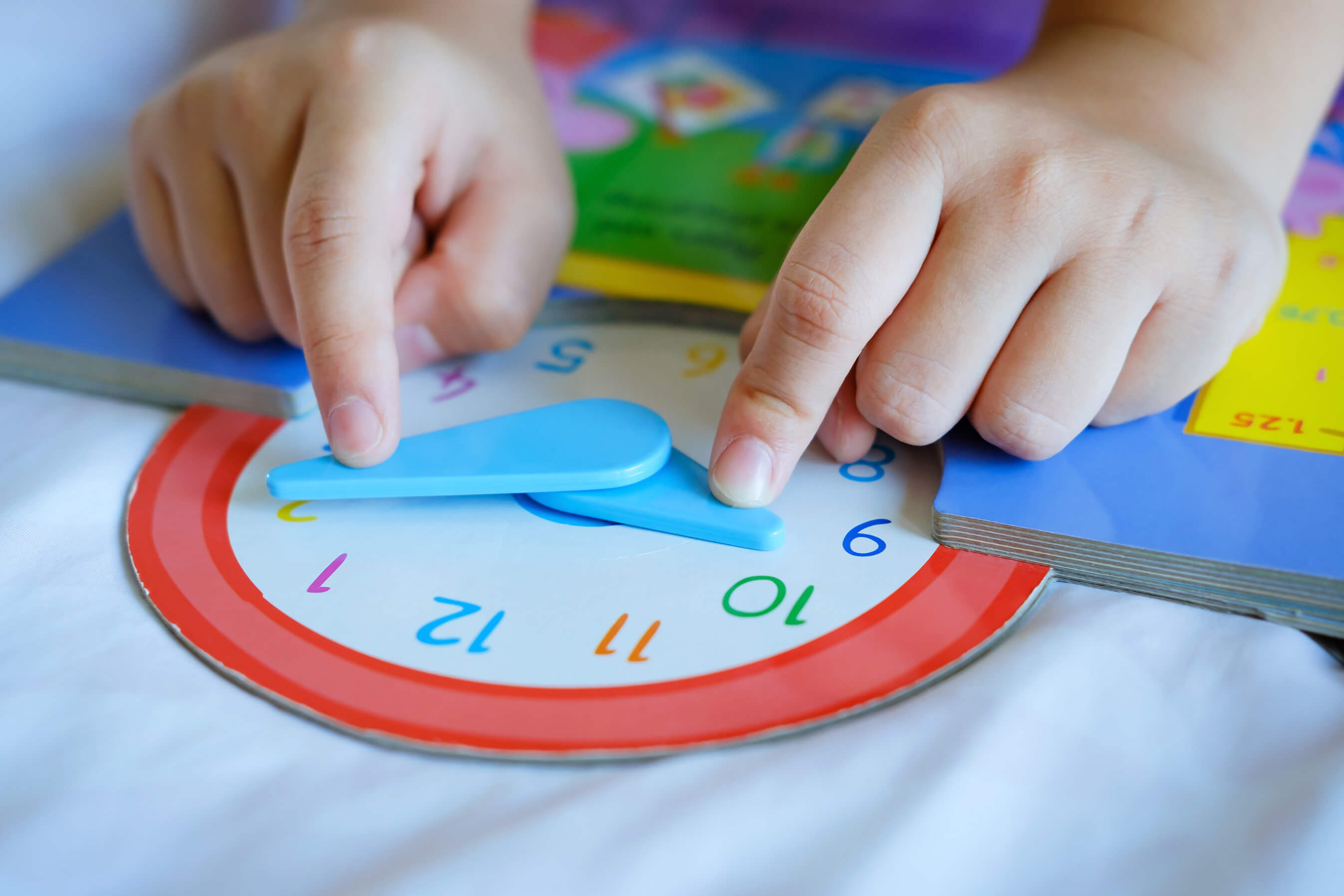 Child using a toy clock to learn about time