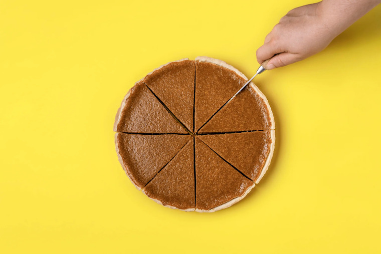 A close-up of a person cutting a cake on a bright yellow surface, showcasing an engaging way to learn about fractions.