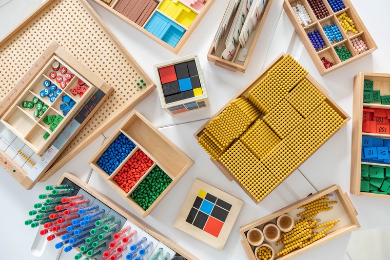 Math manipulatives arranged in trays, including base ten blocks, counting beads, number tiles, and fraction squares