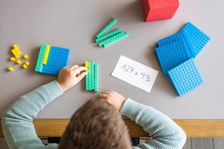 Student using base ten blocks to represent and solve a multi-digit addition problem
