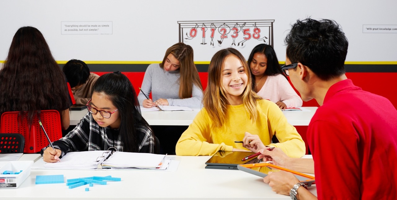 A tutor guides students through homework assignments, promoting engagement and understanding in a classroom setting.