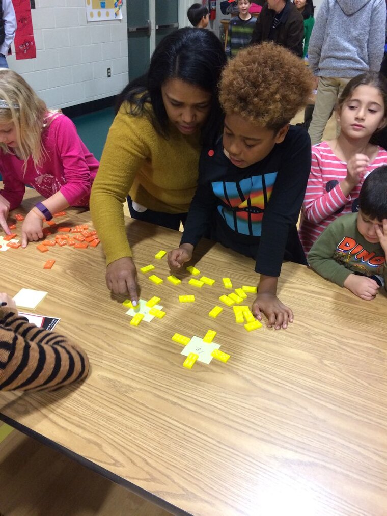 A woman and children joyfully playing together with colorful paper cutouts on a bright, sunny day.