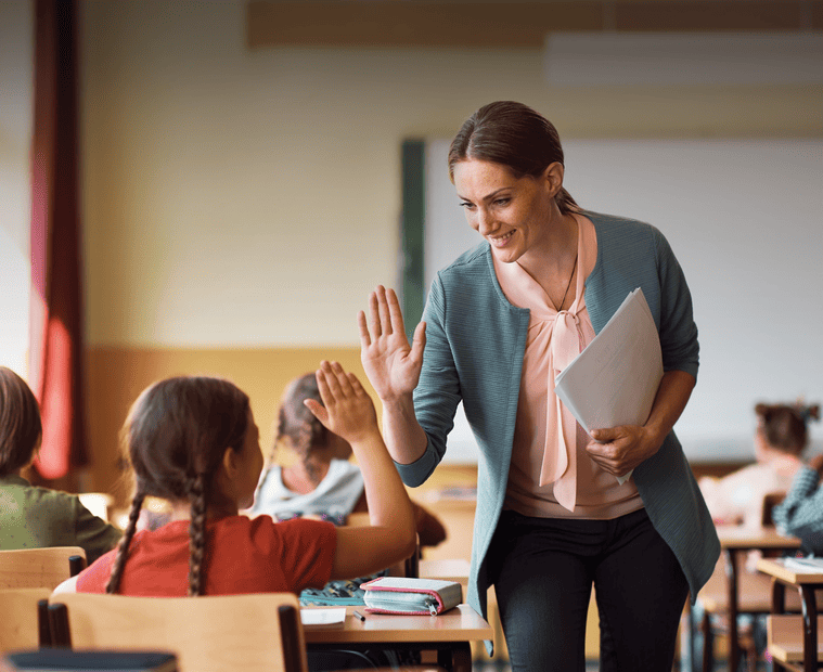 A teacher giving high fives to excited students in a vibrant classroom setting.