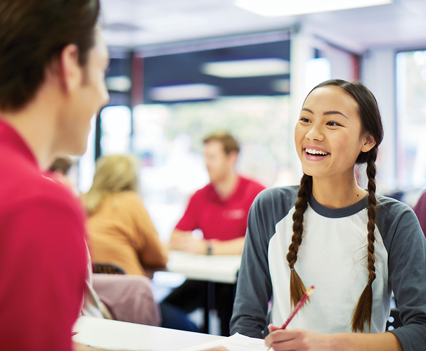 Smiling student talks with a Mathnasium instructor during a personalized tutoring session, reflecting the supportive, face-to-face learning environment