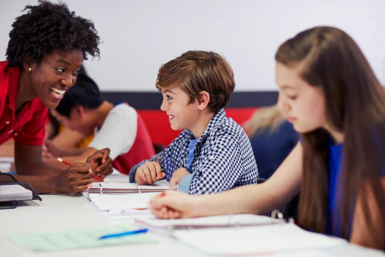 A tutor guides students through homework assignments, promoting engagement and understanding in a classroom setting.