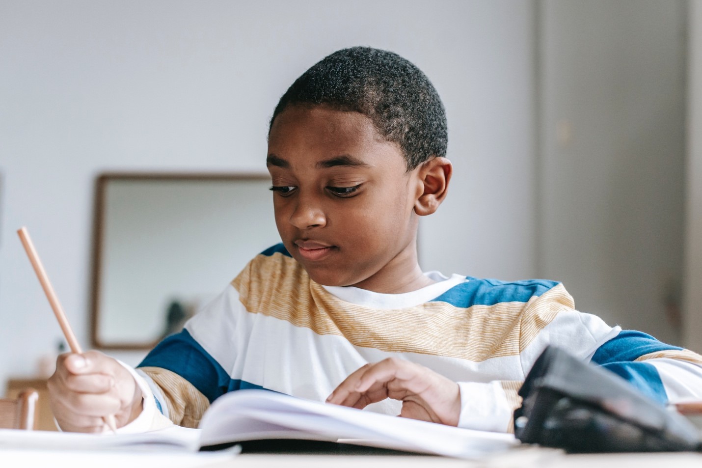 Child-working-on-a-math-problem-with-a-notebook-and-sitting-at-a-desk.jpg