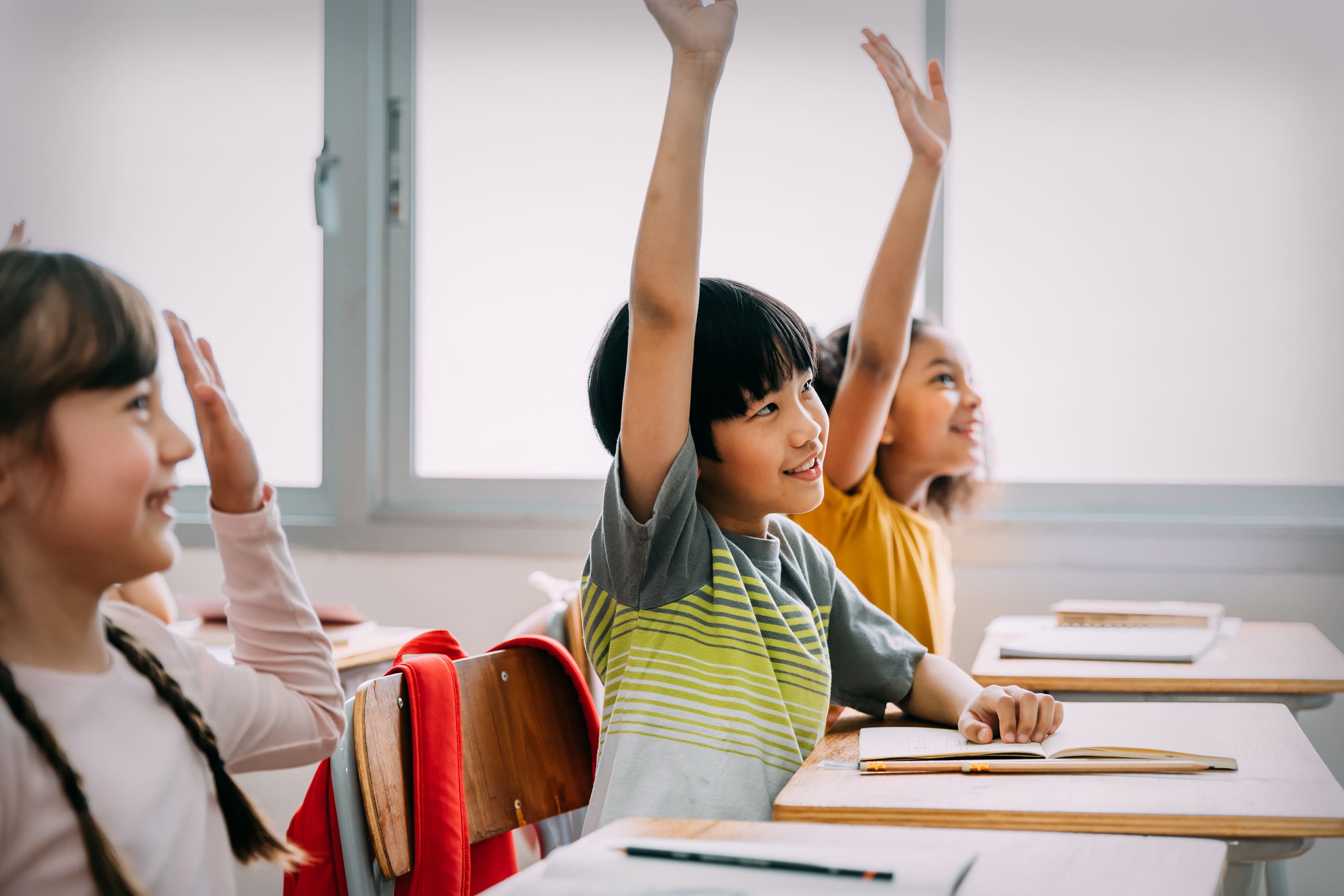 Students eagerly raising their hands to answer a math question.