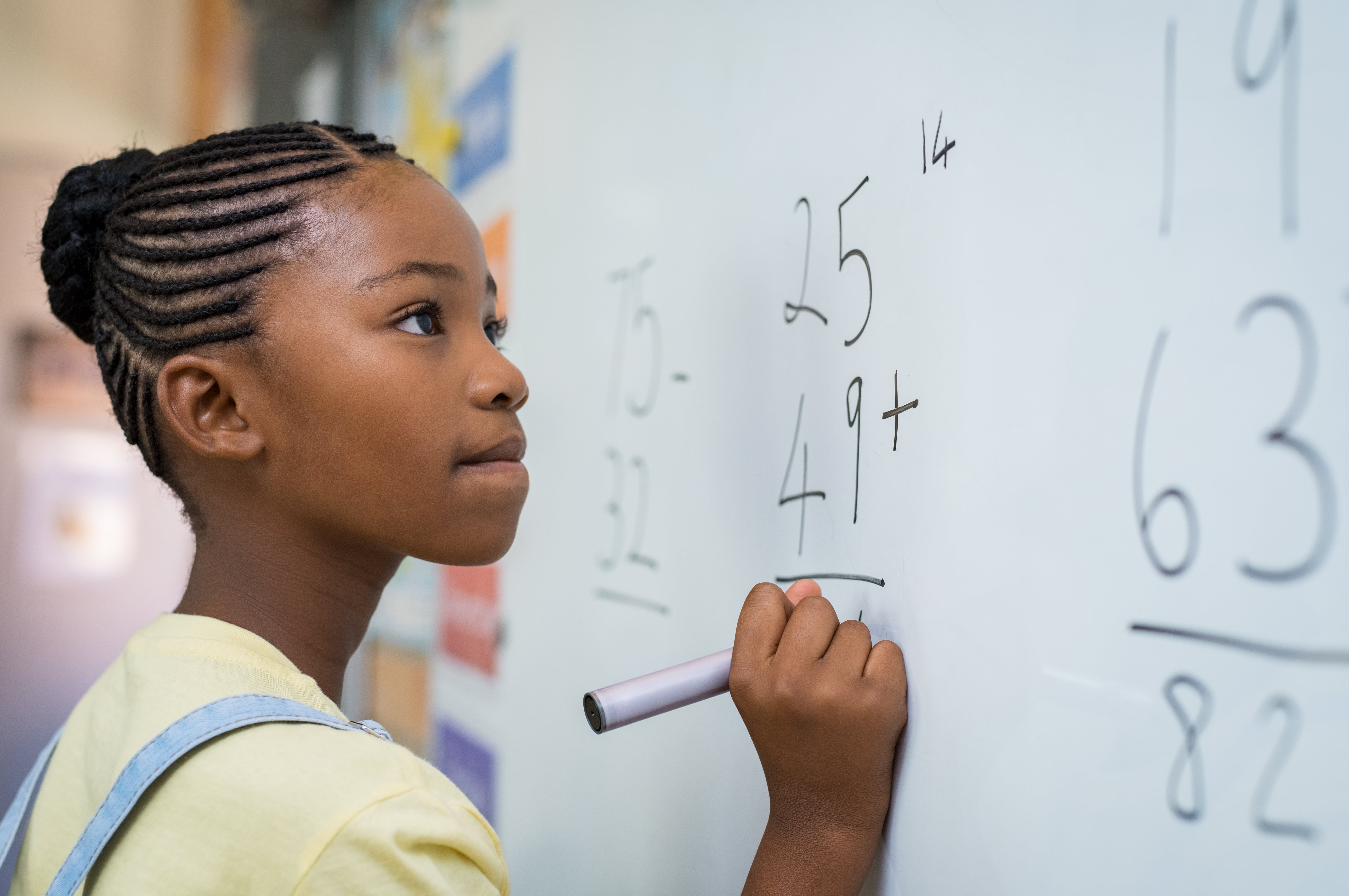 Young girl solving a math problem on the white board.