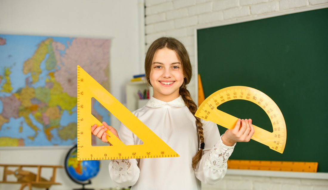 An elementary school student in a math classroom using rulers