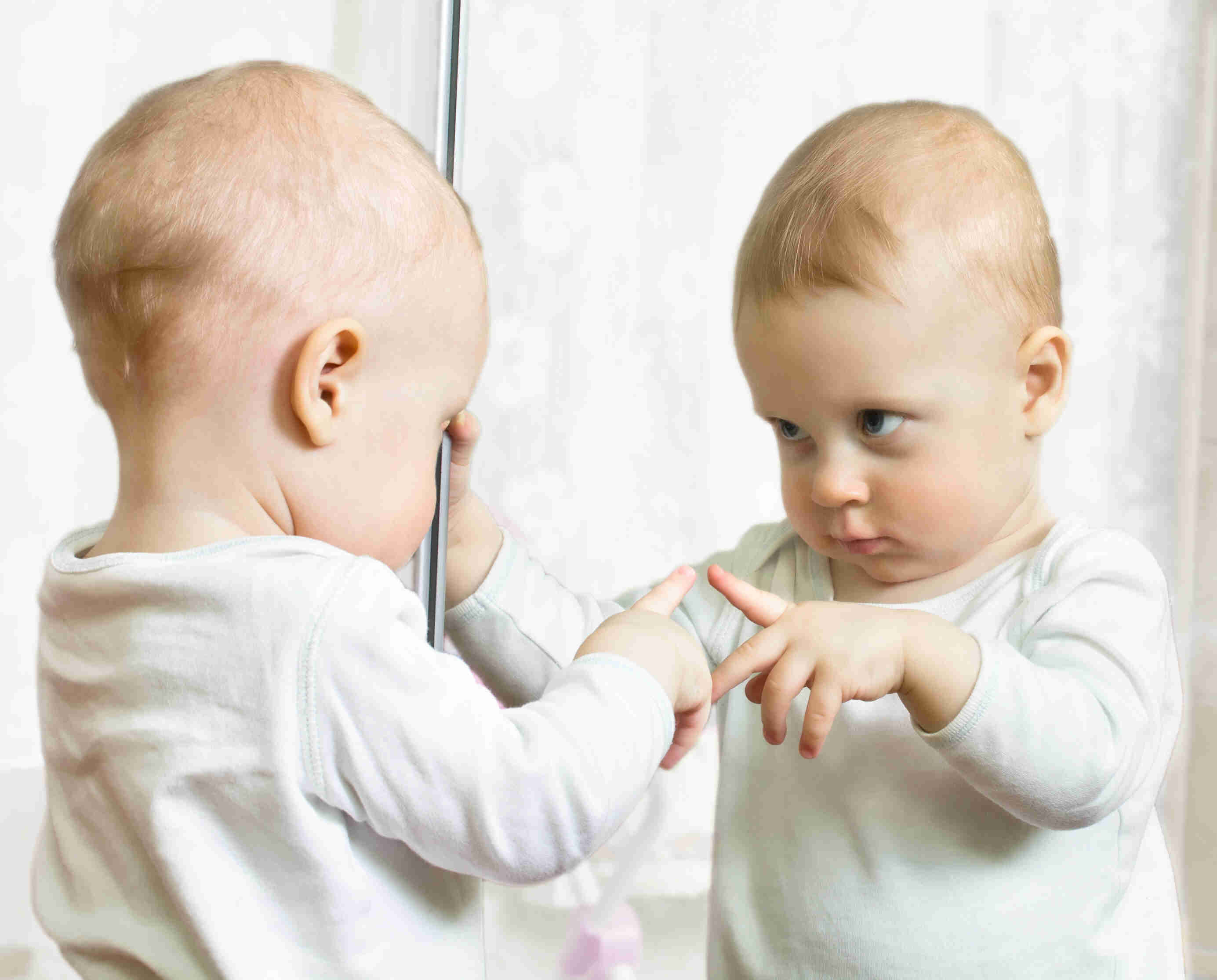 Toddler next to a mirror.