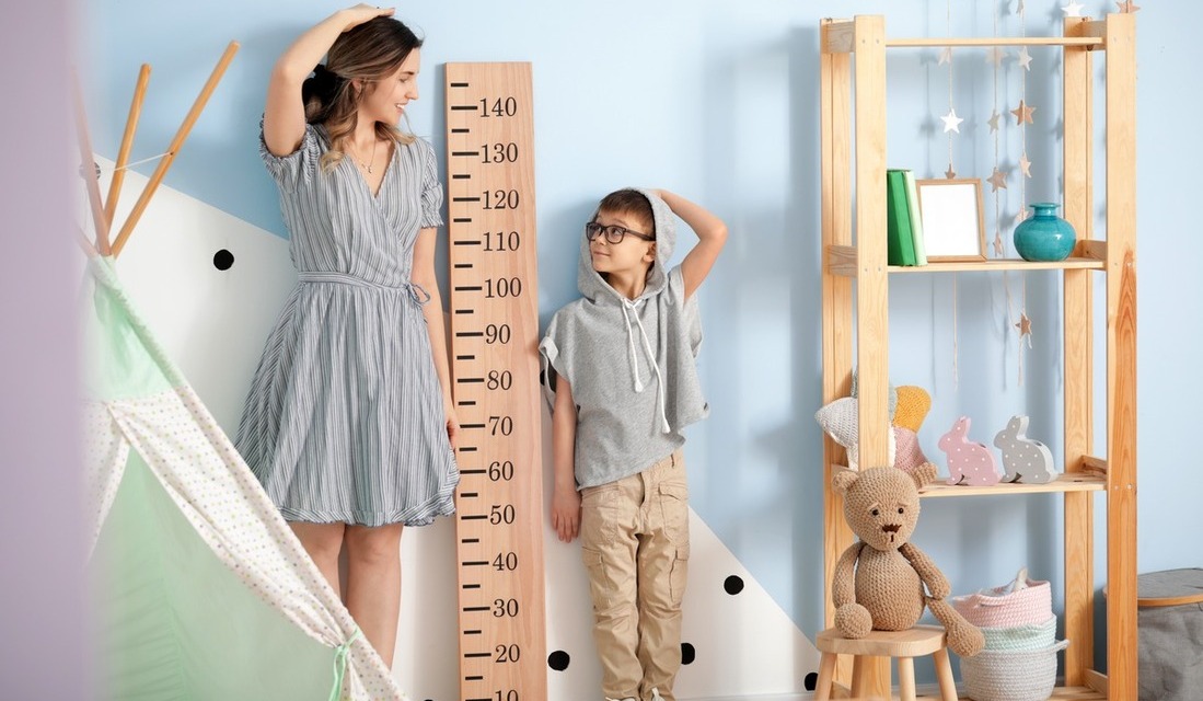 Mom and son compering their height against a huge ruler