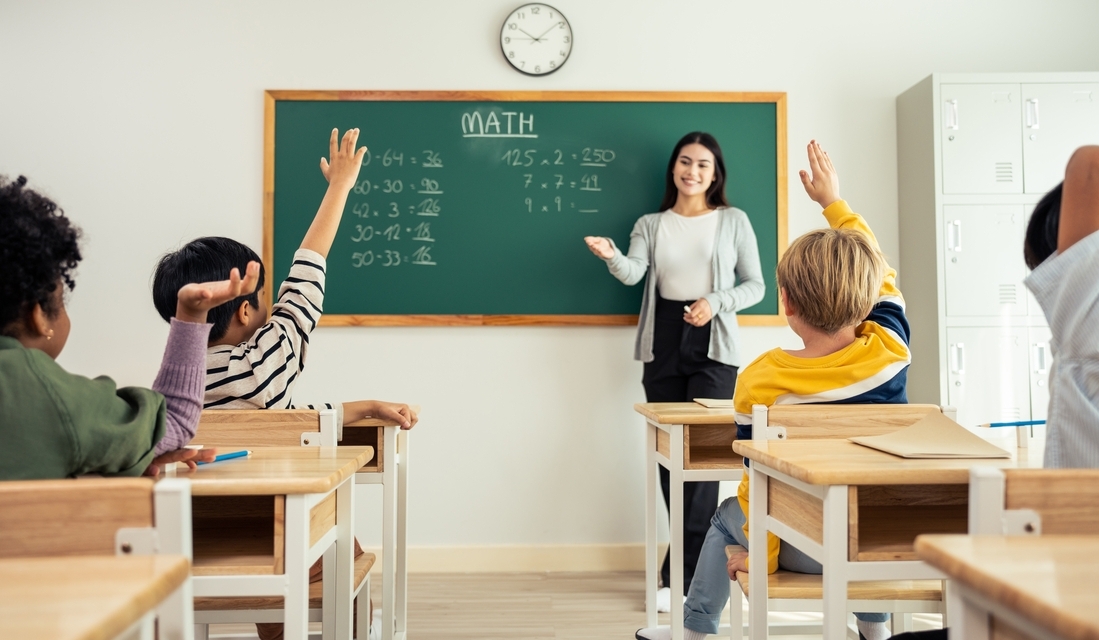 Full math classroom with students raising hands to answer to teacher's question
