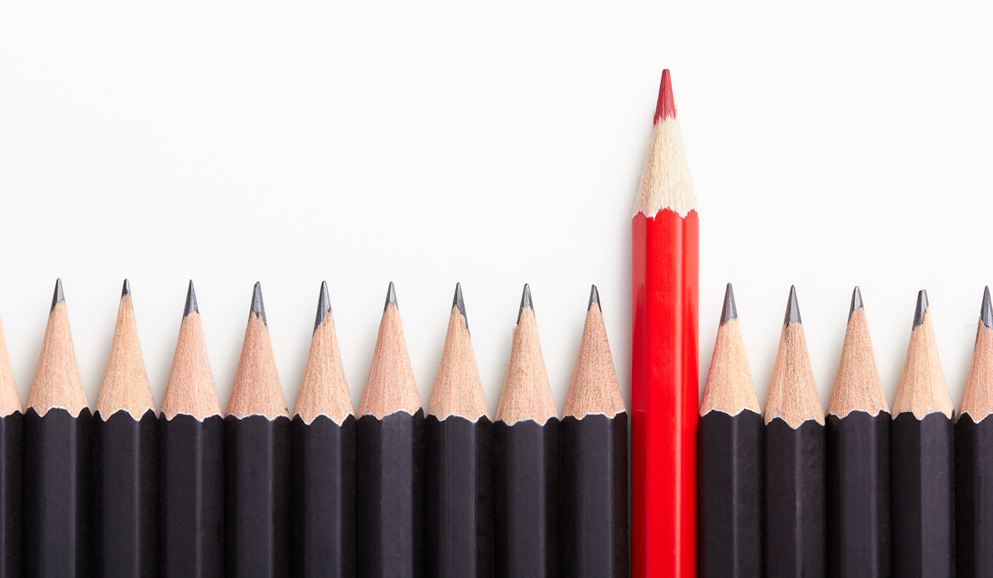 A row of black pencils with one red pencil standing out in the middle, symbolizing an outlier