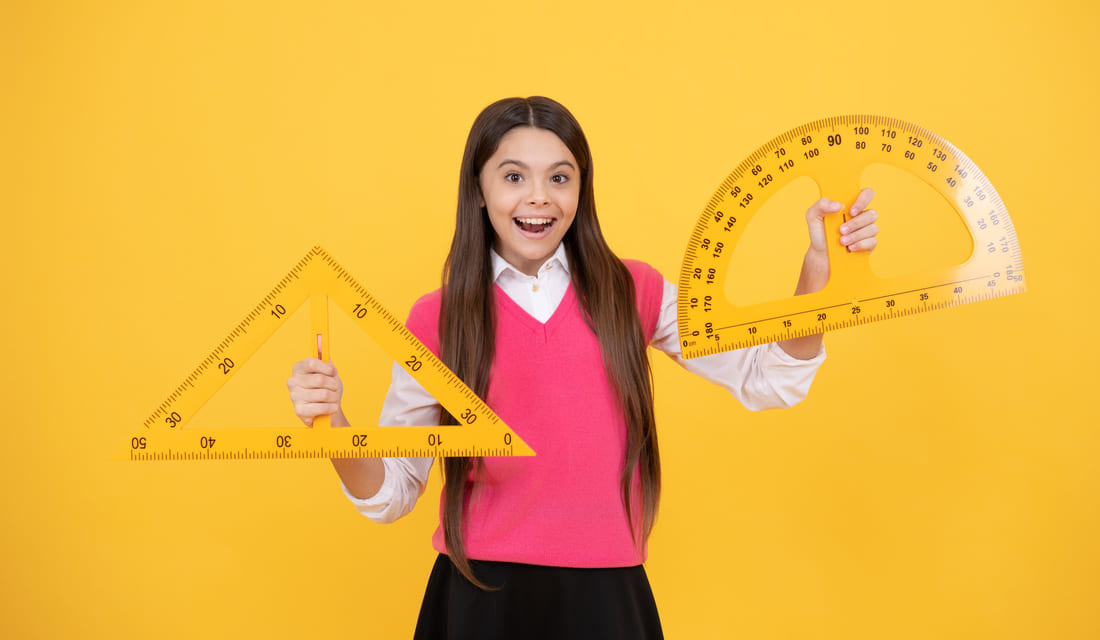 Girl holding geometry tools, including a triangle ruler and protractor.