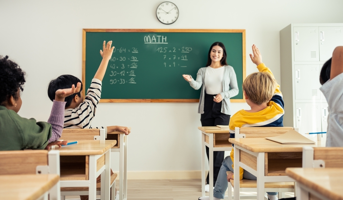 Group of math students learn with their math teacher in classroom at elementary school.