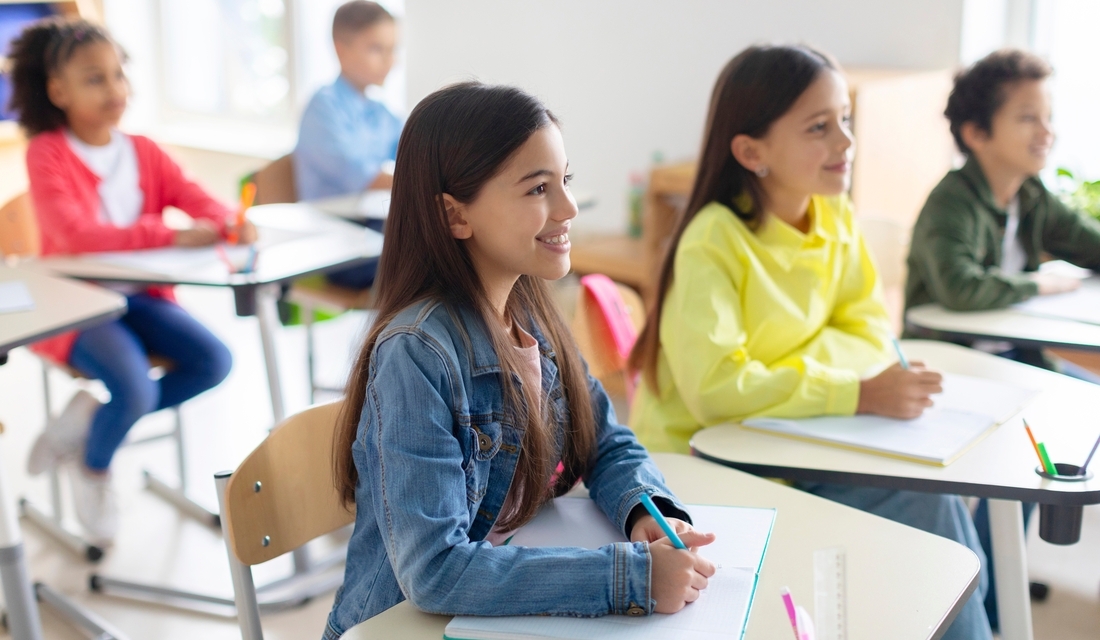 Middle school students engaged in a math class, smiling and writing