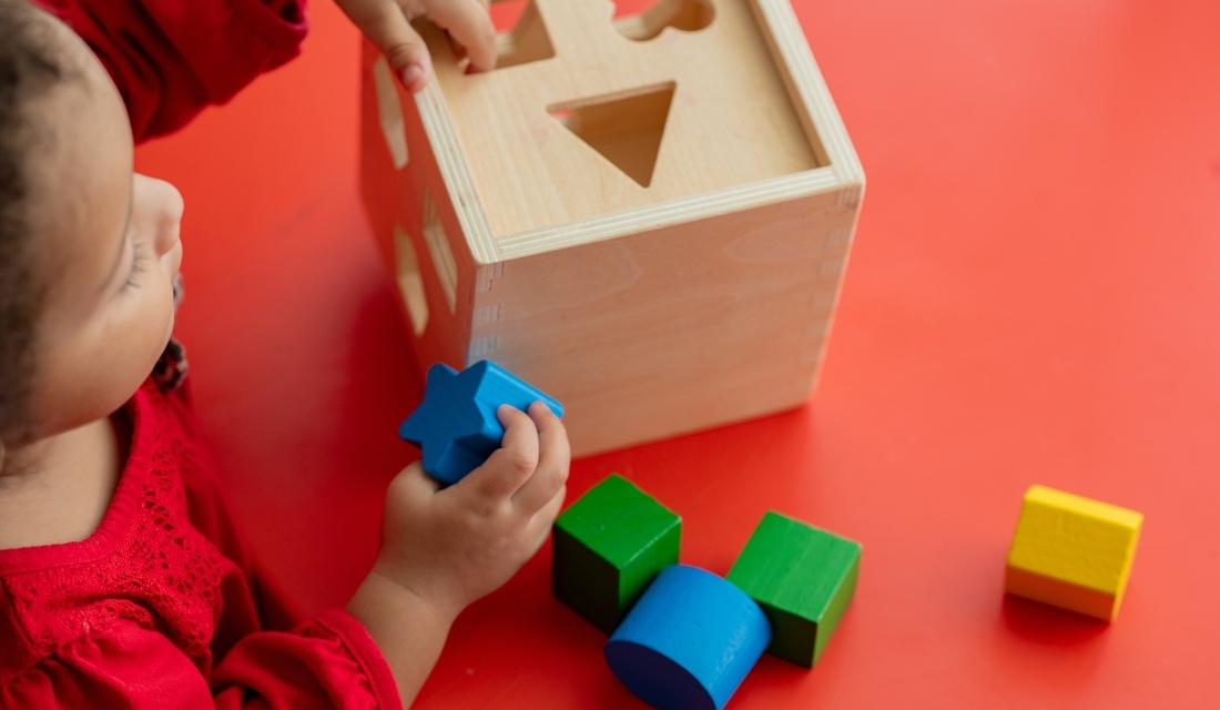Young child playing with a shape sorter toy, exploring shapes and sizes