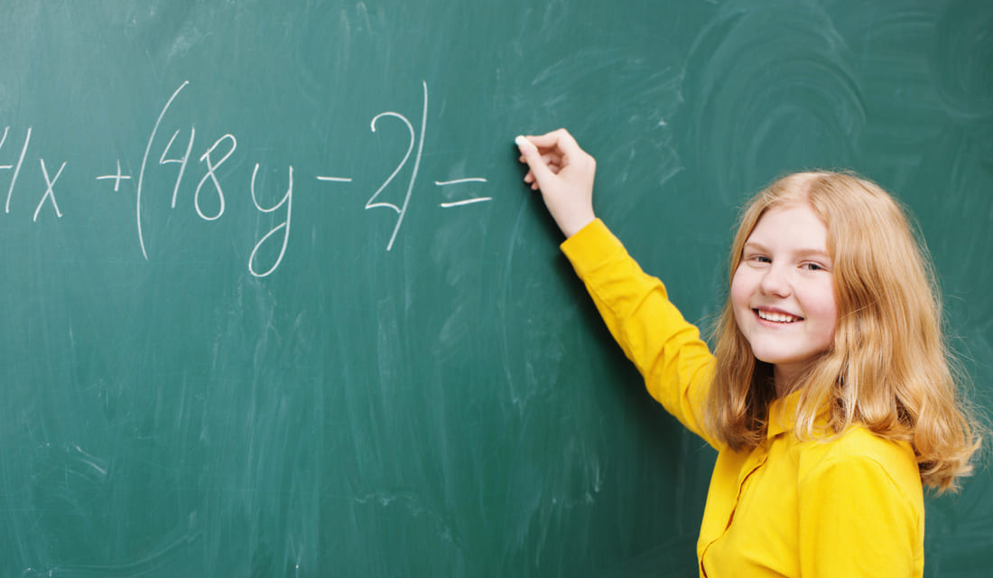 A girl at the blackboard in a mathematics class solving PEMDAS problem