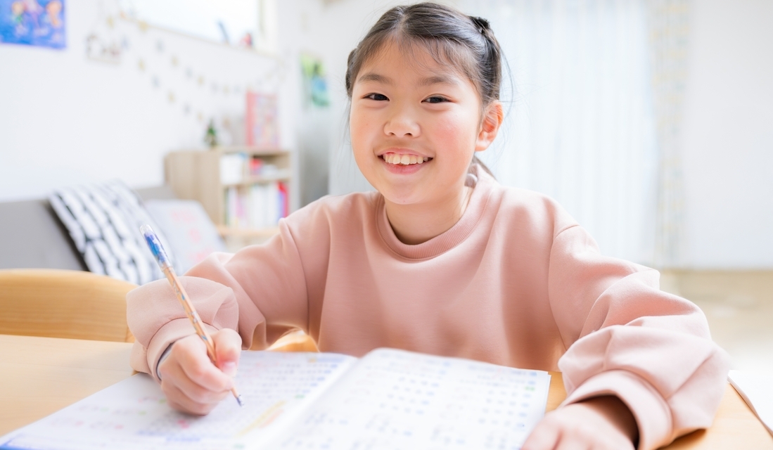 Smiling 5th grade girl studying math at home