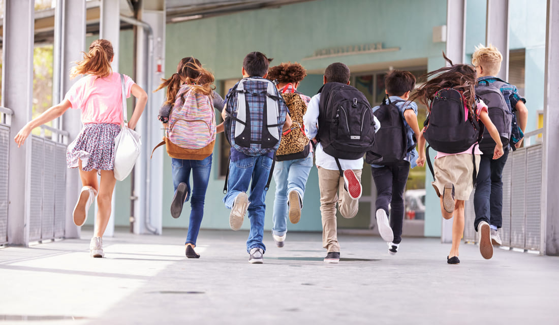 Students running toward school on the first day back, ready for math learning