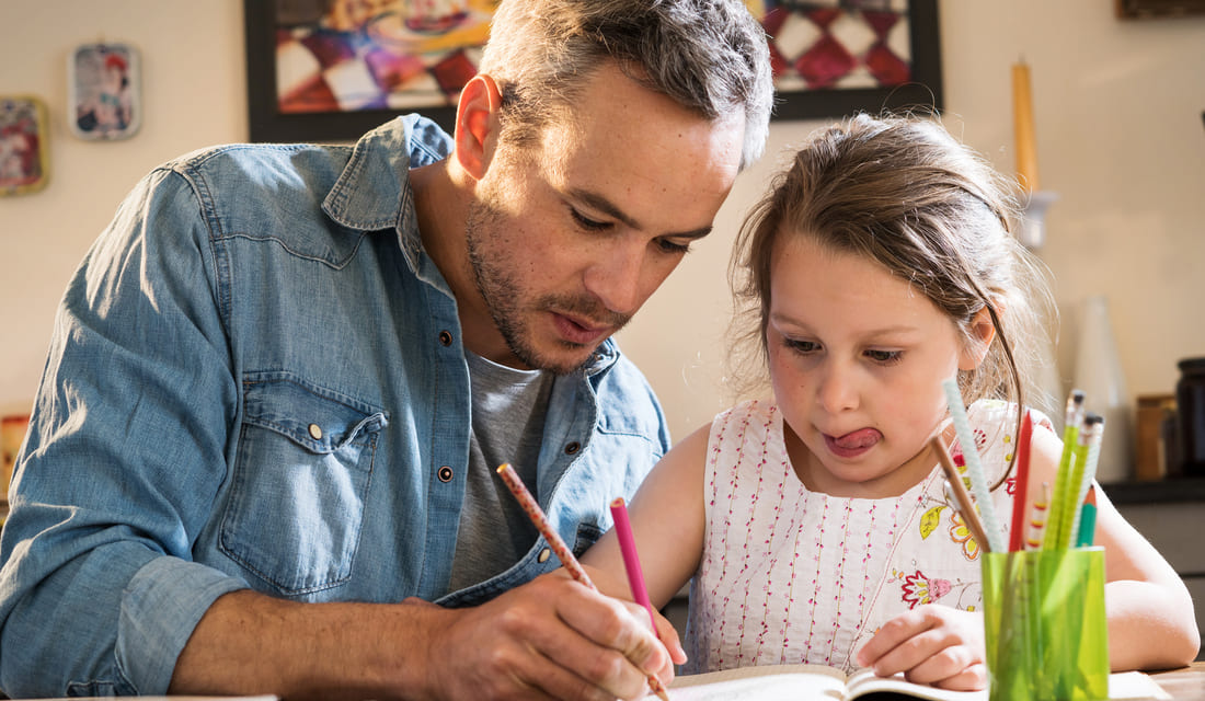 Father helping young daughter with math homework at home