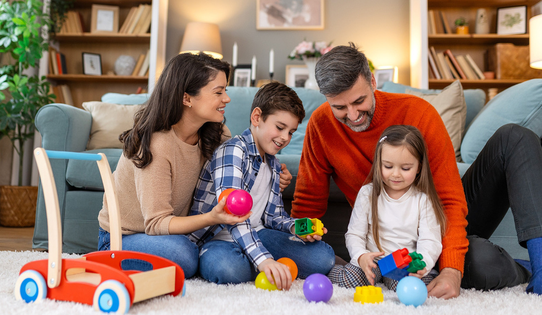 A family joyfully playing with colorful toys on the floor, surrounded by laughter and smiles.