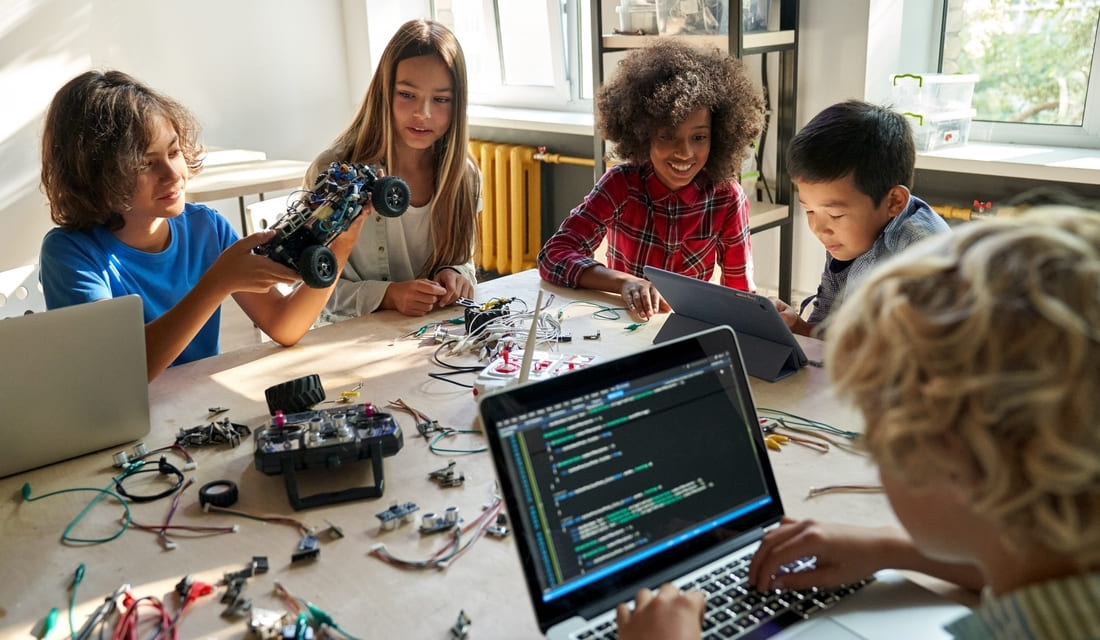 Children collaborating on electronics projects at a table, focused on assembling and experimenting with various components.