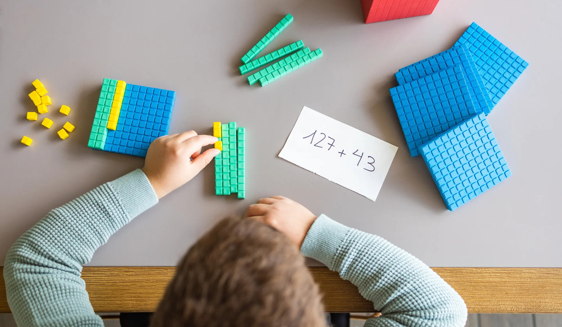 A young child engaged in a math activity, constructing solutions with various Lego pieces.