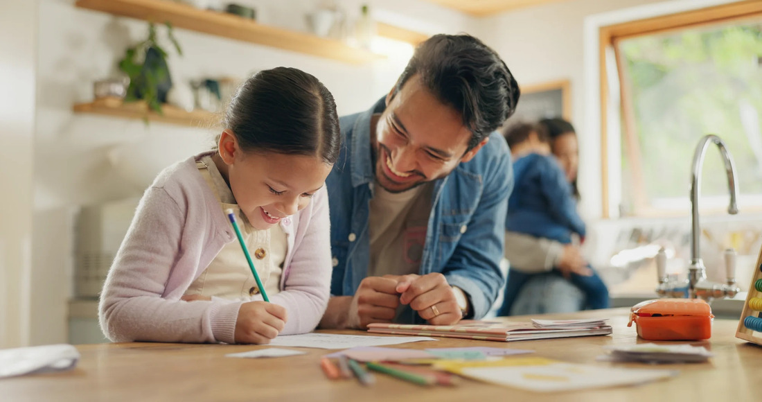 A father and daughter work together on a creative project, demonstrating teamwork and concentration at a workspace.