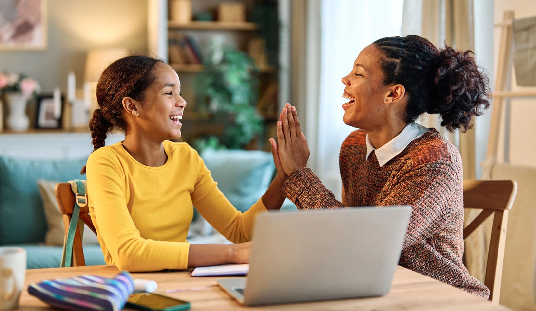 A mother and daughter are seated at a table, their hands joined, symbolizing love and togetherness.
